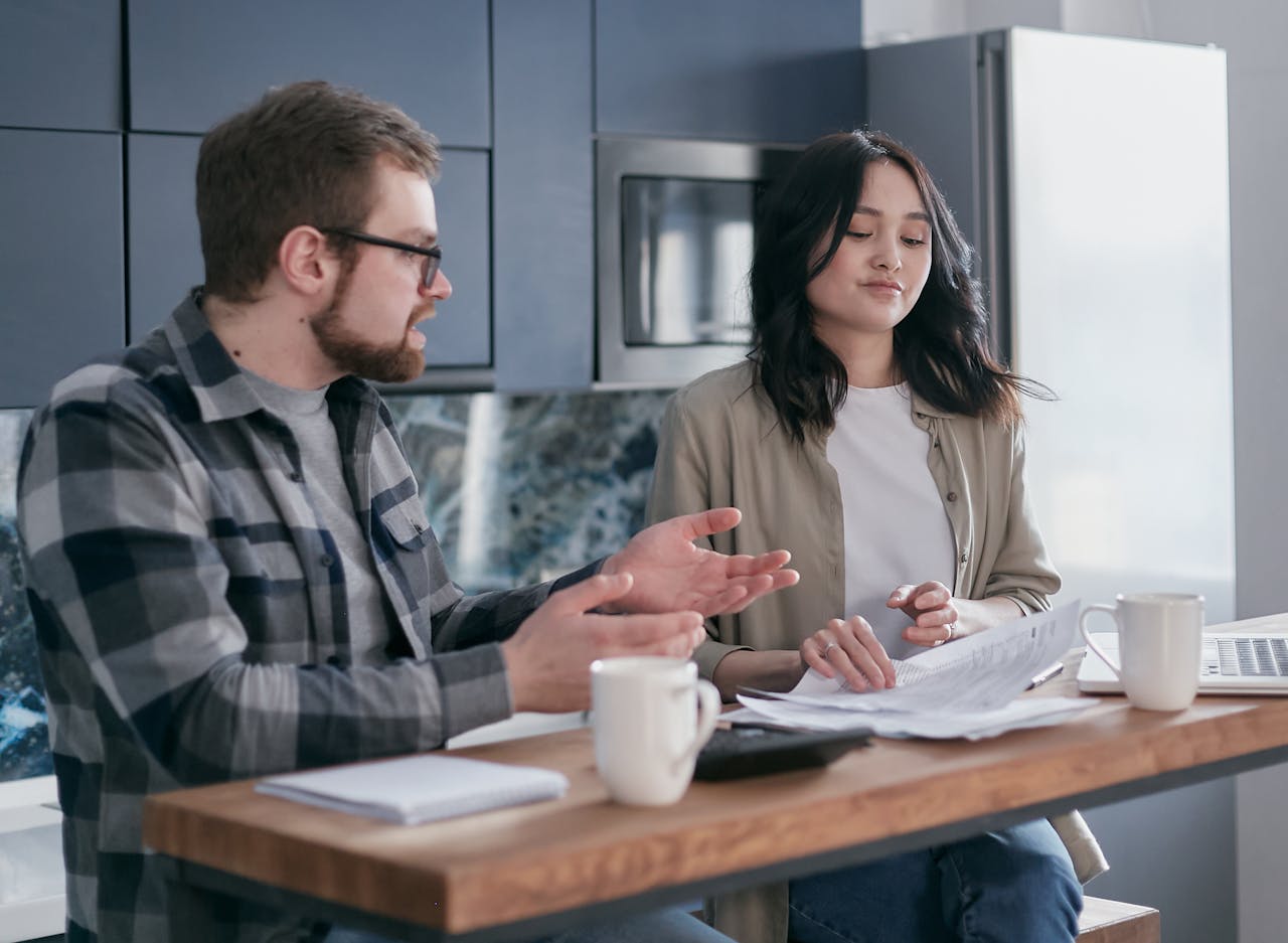 about-01 A couple reviewing financial documents in their kitchen, appearing focused and concerned.